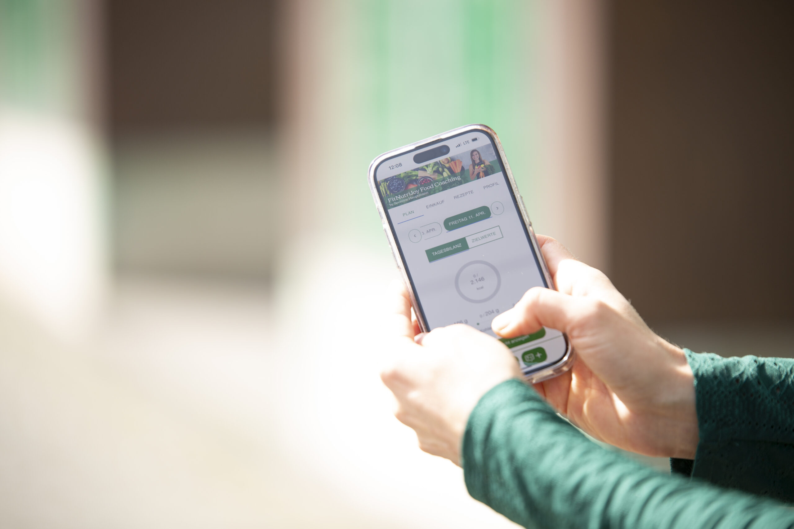 Detailansicht von Severine Hauptmanns Händen die Handy mit FitNutriJoy App zeigen