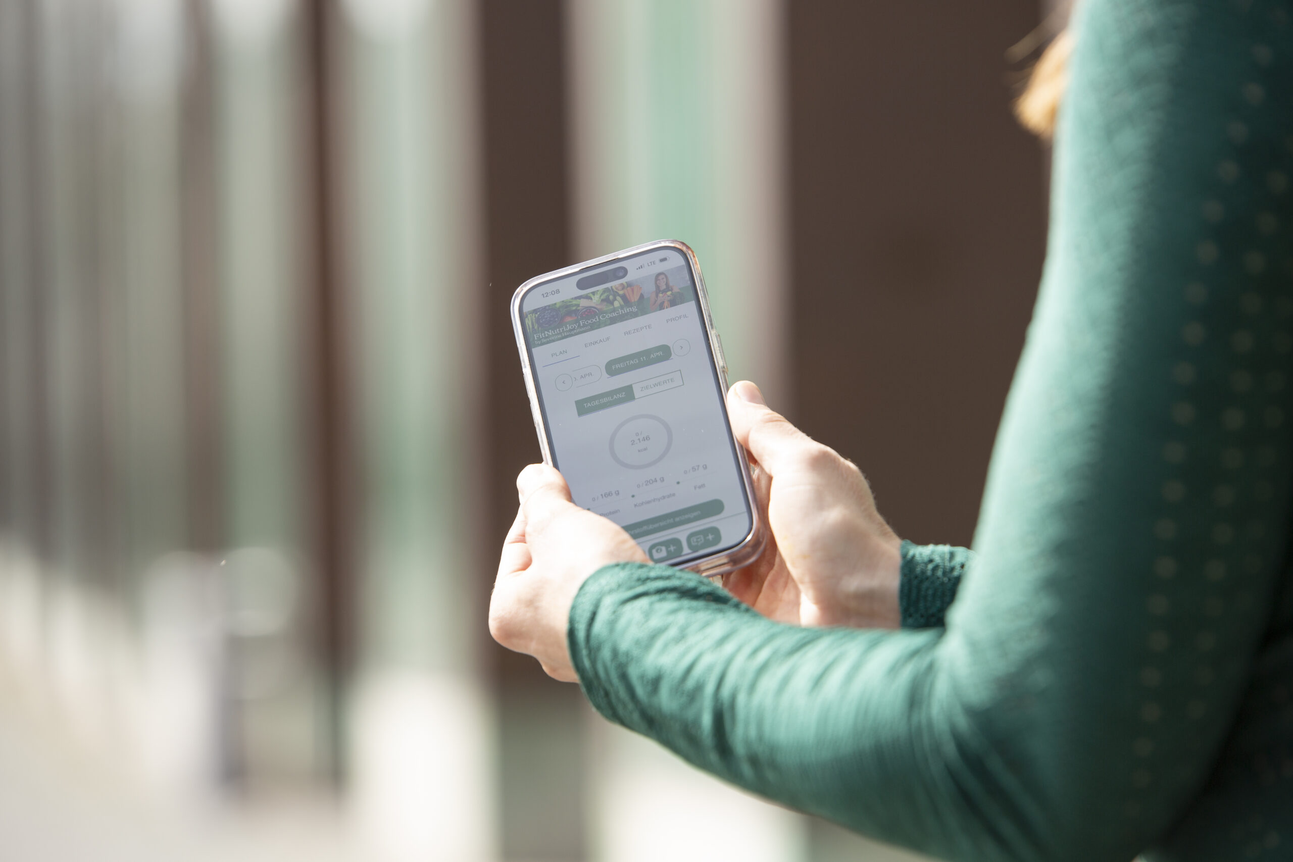 Detailansicht von Severine Hauptmanns Händen die Handy mit FitNutriJoy App zeigen