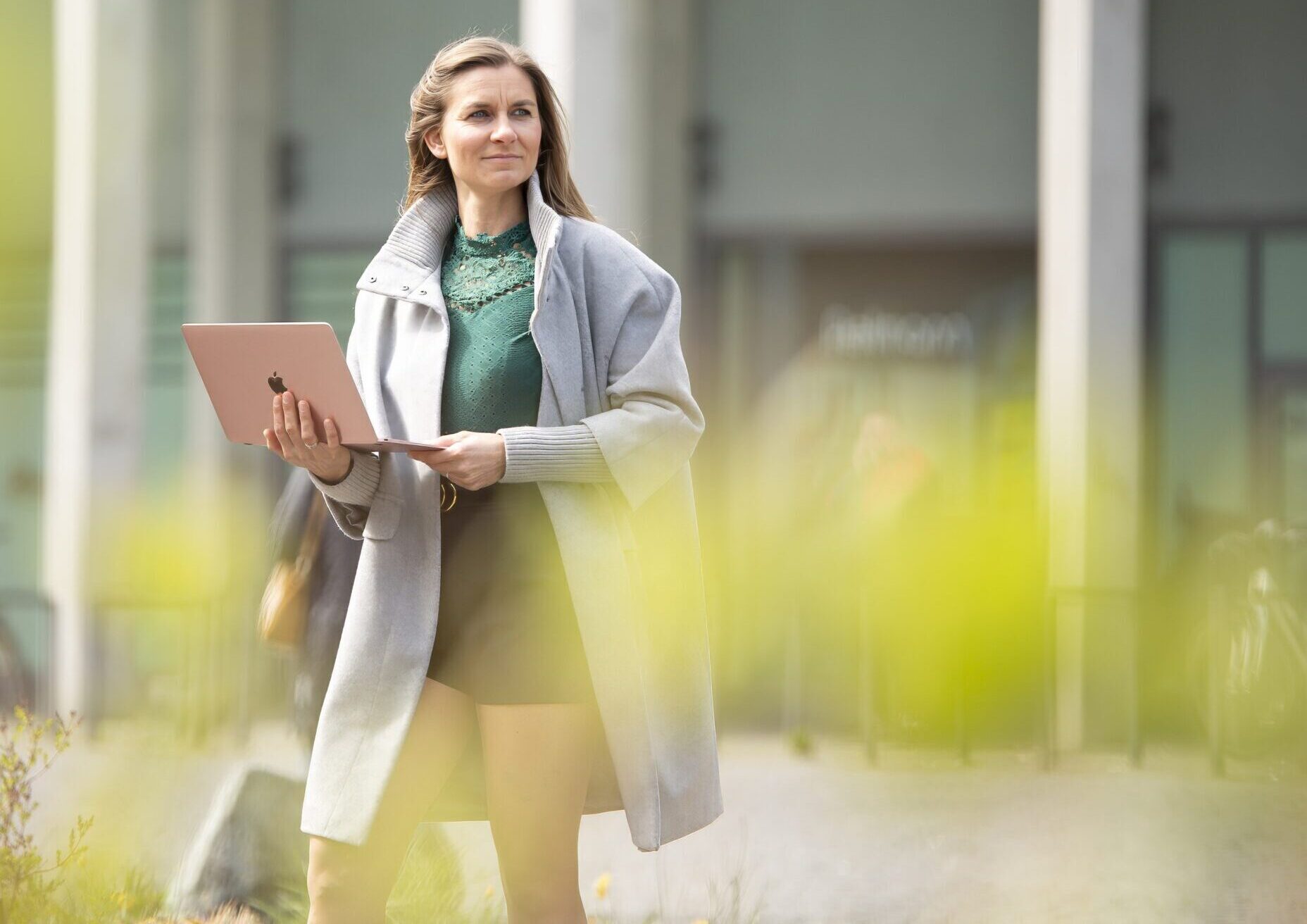 Severine Hauptmann steht und hat offen Laptop in der Hand schaut in die Ferne